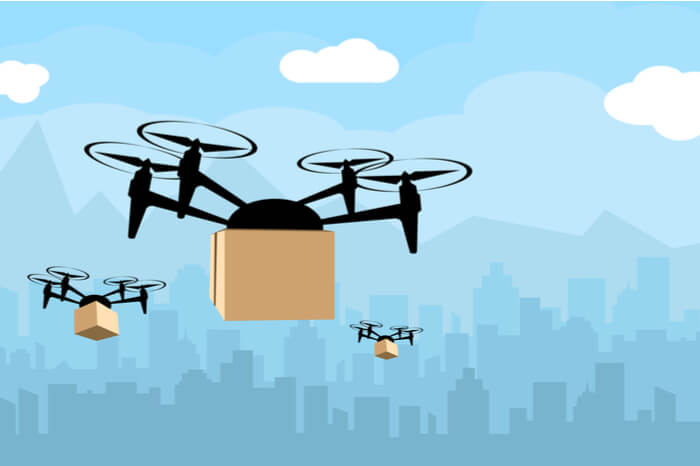 Drei Drohnen mit Paketen vor blauem Stadt-Hintergrund 