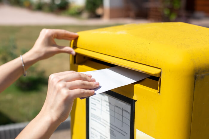 Person steckt Brief in Deutsche Post Briefkasten