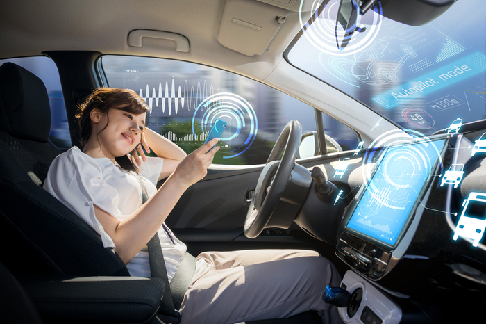 Cockpit autonomes Fahrzeug Frau am Smartphone auf dem Rahrersitz