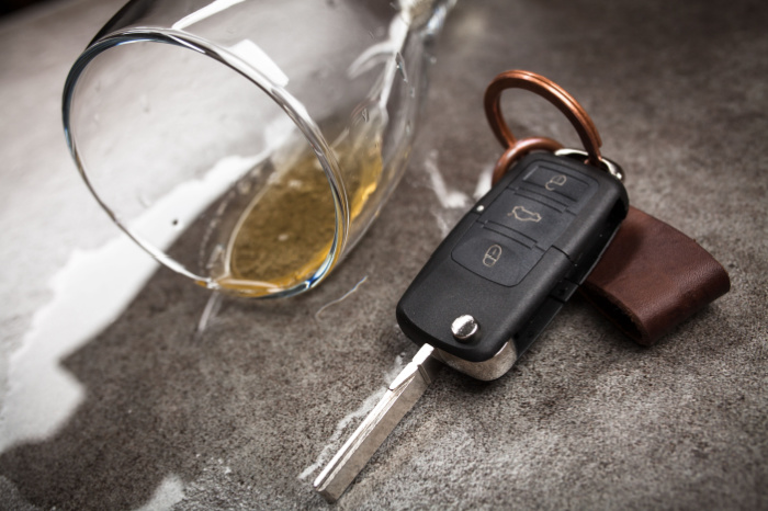 Umgekipptes Alkoholglas und Autoschlüssel