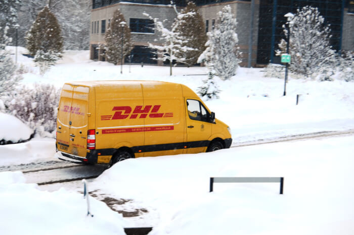DHL-Lieferwagen fährt durch verschneite Straßen