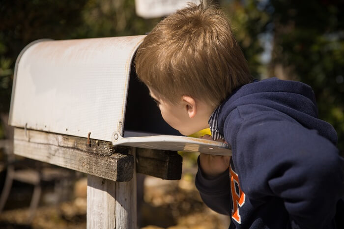 Junge schaut in Briefkasten nach Post