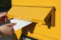 Brief wird in Briefkasten gesteckt