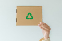 Hand hält Karton mit Recycling-Zeichen