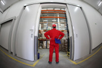 A fish eye view of a worker standing in the doorway of a modern industrial facility.